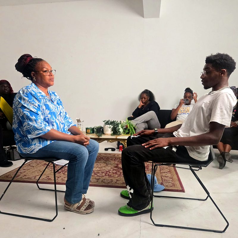 A facilitator and a young man practising a one-to-one conversation while a group watches