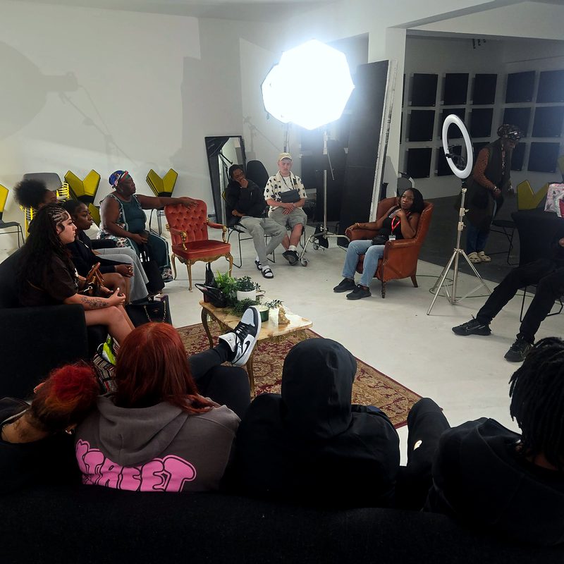Young people and facilitators sitting in a circle in a studio during an Express Yourself session